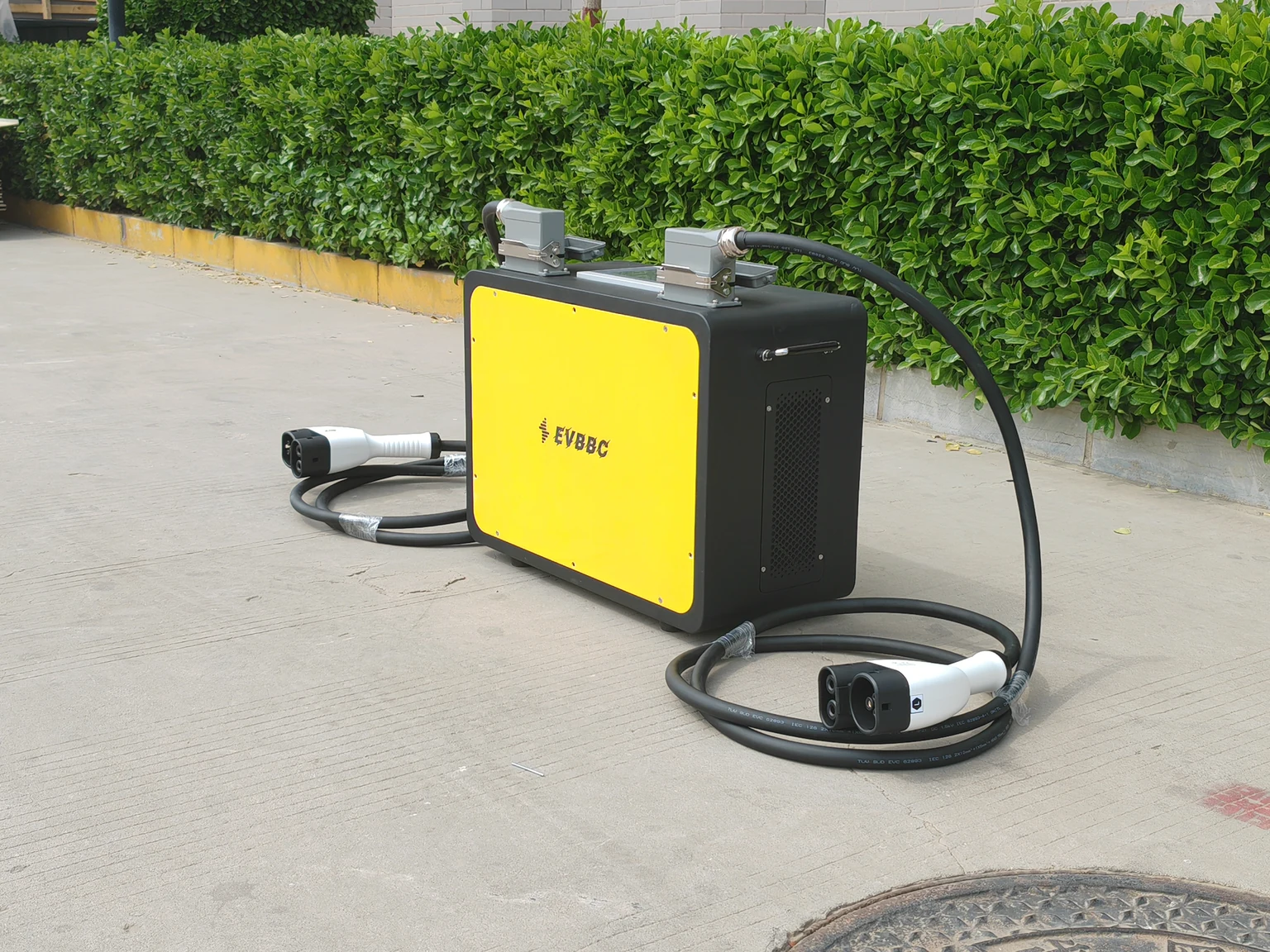 Front-angle photograph of an EVBBC portable vehicle-to-vehicle DC charger with two connector cables
